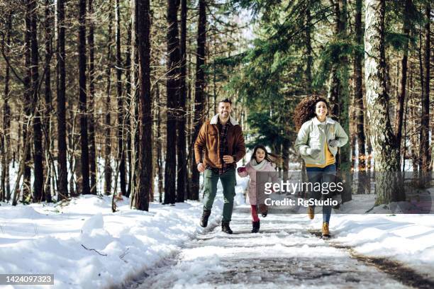 girl running and enjoying with mom and dad during their winter vacation - girl in winter coat studio stock pictures, royalty-free photos & images