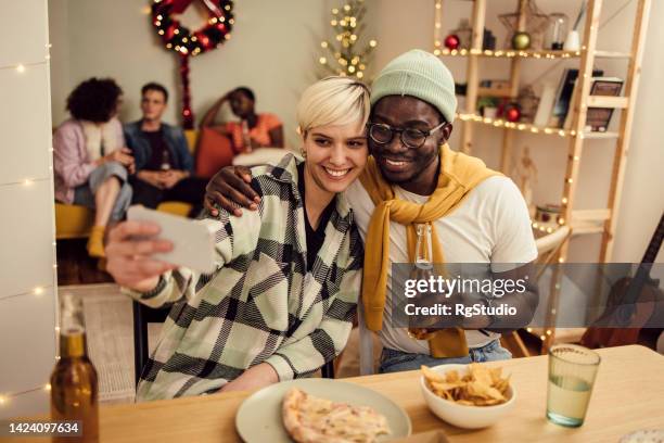 mädchen und ihre afroamerikanische freundin machen ein selfie während einer silvesterparty zu hause - 18 23 monate stock-fotos und bilder