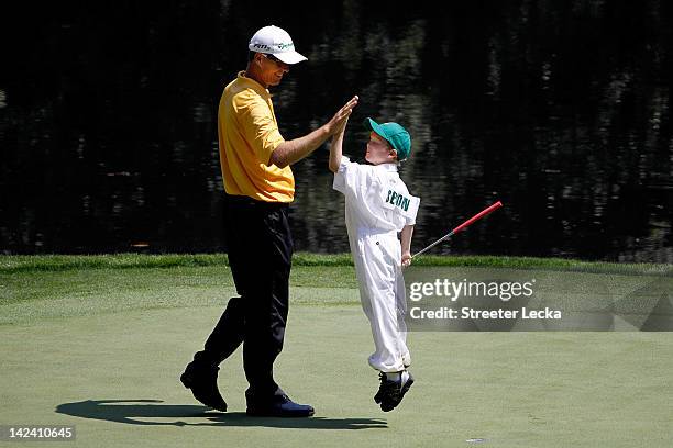 John Senden of Australia high fives his son Jacob during the Par 3 Contest prior to the start of the 2012 Masters Tournament at Augusta National Golf...