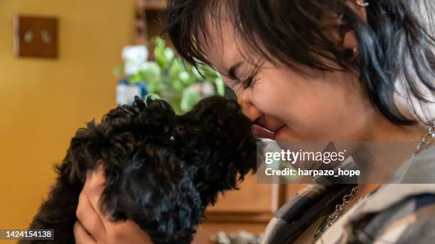 puppy licking a teenage girl. - black poodle stockfoto's en -beelden