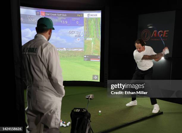 Player Keith Yandle , dressed as a golf caddie, watches Auston Matthews of the Toronto Maple Leafs take a swing at a golf simulator during the 2022...