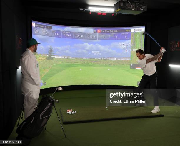 Player Keith Yandle , dressed as a golf caddie, watches Auston Matthews of the Toronto Maple Leafs take a swing at a golf simulator during the 2022...