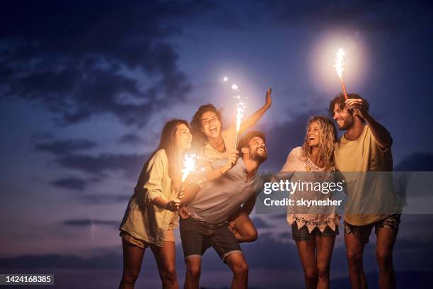joyeux amis s’amusant avec des torches enflammées par nuit. - fête de plage photos et images de collection
