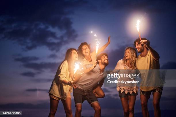 cheerful friends having fun with flaming torches by night. - praia noite imagens e fotografias de stock