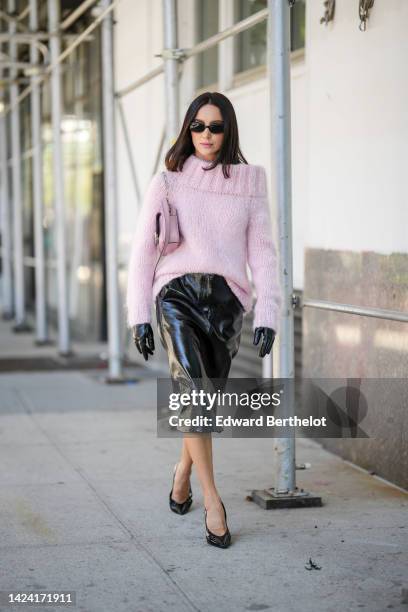 Mary Leest wears black sunglasses, a pale purple wool shoulder-off / long sleeves / oversized pullover, black shiny varnished leather gloves, a matte...