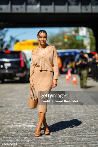 Tamara Kalinic wears gold Clash earrings from Cartier, a gold Juste Un Clou necklace from Cartier, a beige brown wool long sleeves / V-neck /...