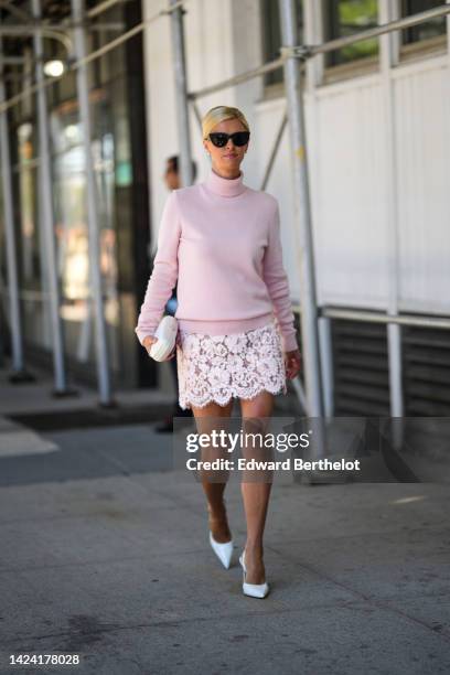 Guest wears black sunglasses, a pale pink wool turtleneck / long sleeves pullover, a white latte flower lace pattern short skirt, a white satin...
