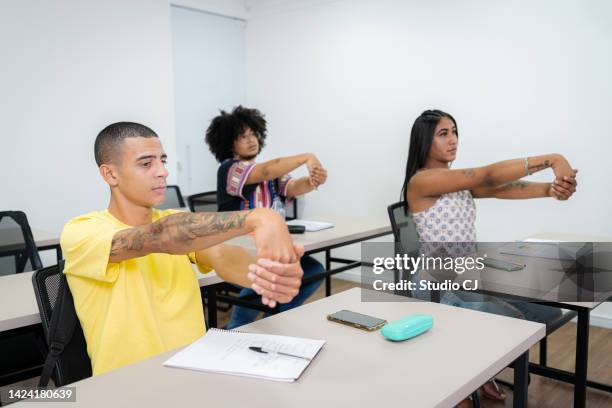 young people in the classroom performing stretching - the millennium stock pictures, royalty-free photos & images