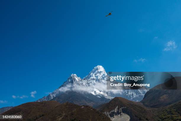 a helicopter flying over mt.ama dablam against blue sky in sagarmāthā national park of nepal. - helicopter view stock pictures, royalty-free photos & images