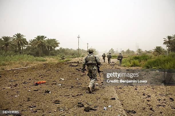 Soldiers search for the remains of three comrades who were killed instantly after the humvee they road in was utterly destroyed by a massive IED on...