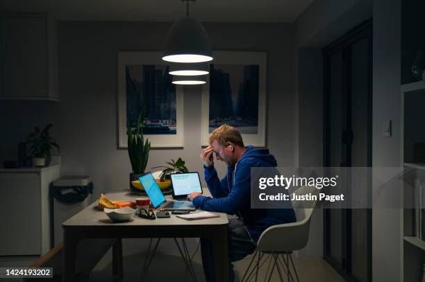 a stressed mature man goes through his home finances at the dining table - debt fotografías e imágenes de stock