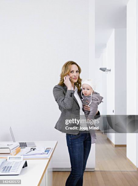 businesswoman on smartphone holding baby - single mother with baby stock pictures, royalty-free photos & images