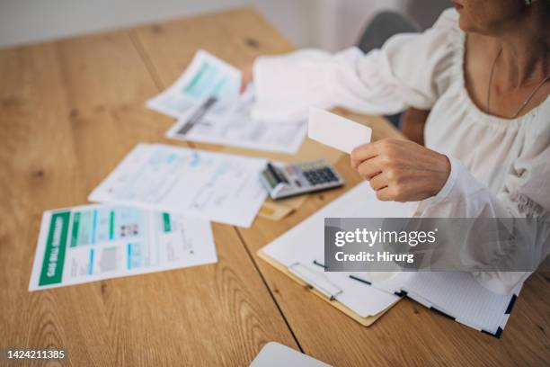 mature woman at home looking at the bills and taxes and trying to calculate and pay them - 法案 個照片及圖片檔