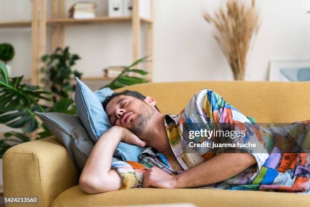 man sleeping on sofa at home. - dormir imagens e fotografias de stock