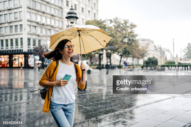 young woman running from the rain - holding umbrella stock pictures, royalty-free photos & images