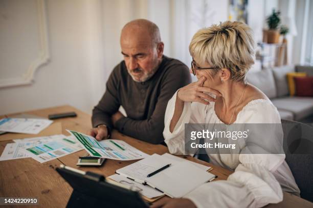 pareja calculando facturas e impuestos y casa y tratando de organizarse para pagarlos - gas prices fotografías e imágenes de stock