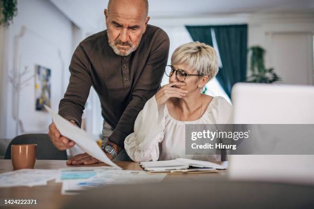 coppia che calcola bollette e tasse e casa e cerca di organizzarsi per pagarle - bolletta foto e immagini stock