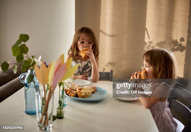 two sisters eating snack at dining table at home - sister imagens e fotografias de stock