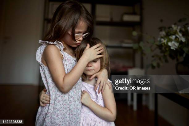 affectionate girl hugging sister at home - schwester stock-fotos und bilder