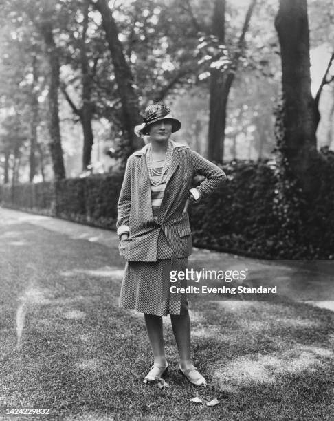 French fashion designer Coco Chanel wearing a design of her own creation poses in a garden on the Rue du Faubourg Saint-Honore, Paris, France, 30th...