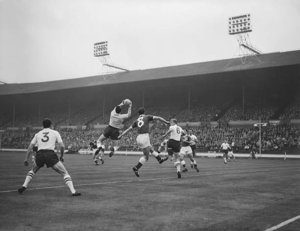 British footballer Ron Springett leaps to make the save from Northern Irish footballer Hugh Barr during the Home Nations Championship between England...
