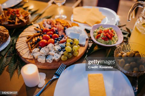 close-up of various cheeses and grapes on a wooden board, placed on a serving table - cheese plate stock pictures, royalty-free photos & images