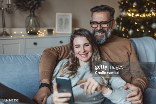 reifes paar zu weihnachten zu hause - christmas smartphone stock-fotos und bilder