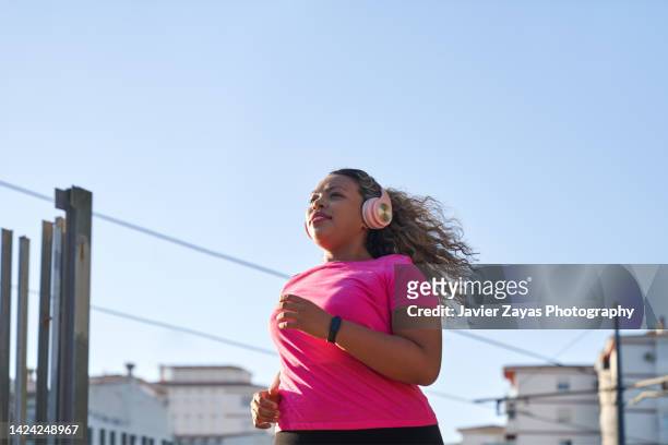 latin woman with large build running in city - happy people running photos et images de collection