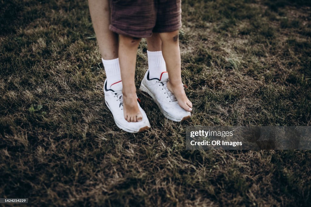 Boy standing on feet of his older brother