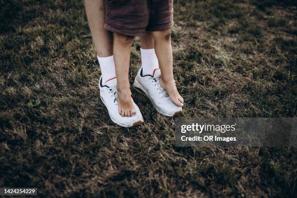boy standing on feet of his older brother - big foot 個照片及圖片檔
