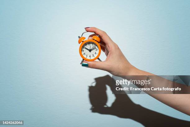 woman's hand holding  alarm clock - frau uhr stock-fotos und bilder