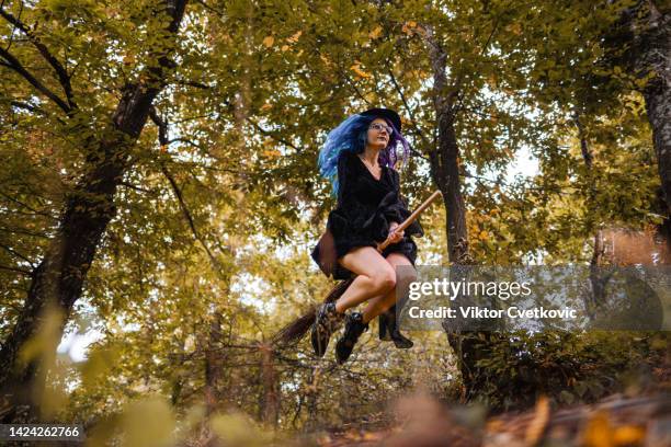 young witch flying on a broom through the woods on halloween - witch flying on broom stock pictures, royalty-free photos & images