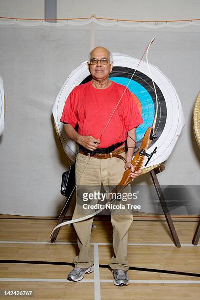 senior archer infront of the target with his bow. - bow and arrow stock pictures, royalty-free photos & images