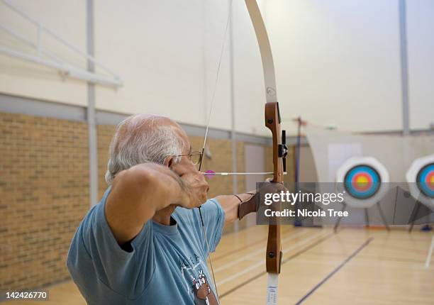 a senior archer aiming at the target. - arco frecce foto e immagini stock