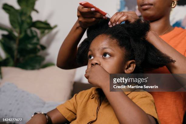 young black girl gets her hair braided by mother - braided hair imagens e fotografias de stock
