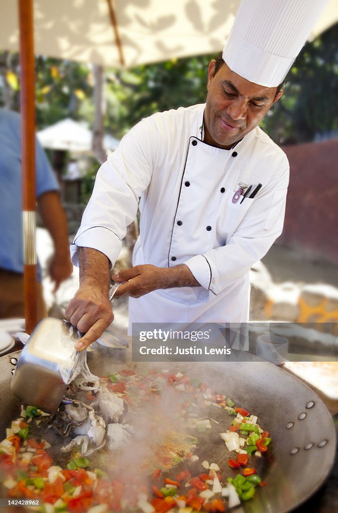 Chef cooking a big bowl of sea food paiya
