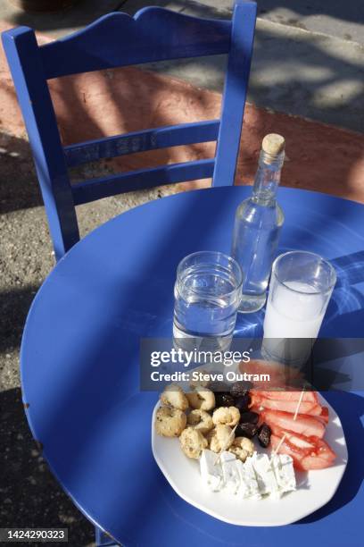 outside taverna table with a glass and bottle of ouzo plus a meze, crete, greece. - ouzo stock pictures, royalty-free photos & images