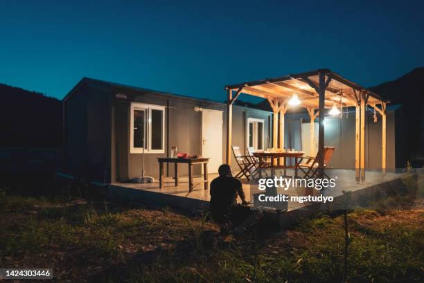 mature man preparing barbecue dinner in backyard of container house. - tijdelijk gebouw stockfoto's en -beelden