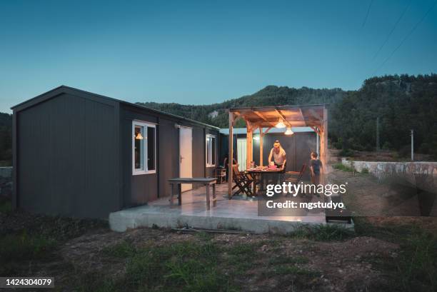 woman with her son preparing dinner table for bbq on patio of alternative container house - tijdelijk gebouw stockfoto's en -beelden