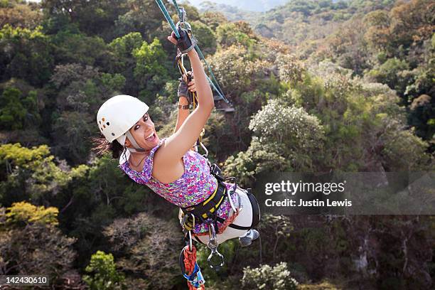 girl smiling while riding a zip line over tree top - puerto vallarta stockfoto's en -beelden