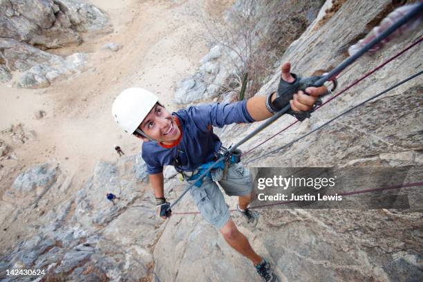 guy repelling down granite wall looking up - teen courage stock pictures, royalty-free photos & images