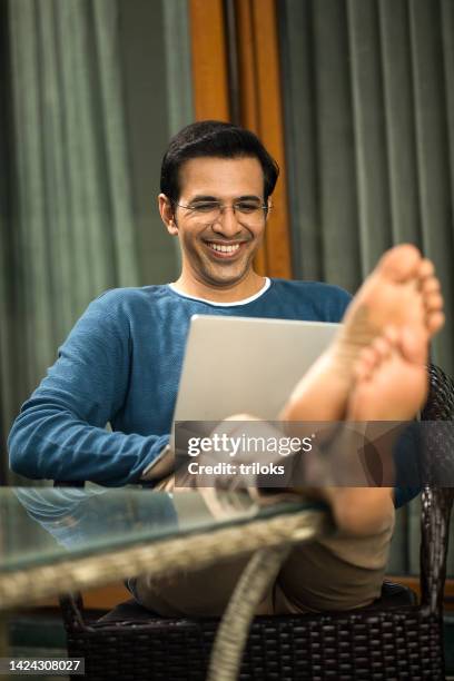 happy man using laptop at home - feet on table bildbanksfoton och bilder