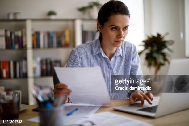 serious mature woman paying her utility bills online - energy bill stockfoto's en -beelden