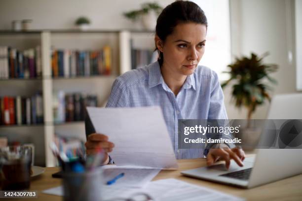 serious mature woman paying her utility bills online - fee stock pictures, royalty-free photos & images