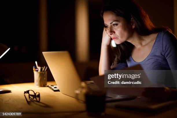 worried mature woman calculating budget and finances at home - crisis planning stock pictures, royalty-free photos & images