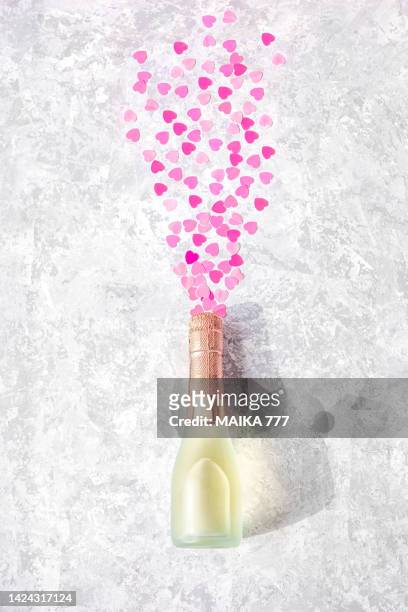 high angle view champagne bottle exploding with pink hearts shaped sequins on gray background. gender reveal party concept. flat lay. - its a girl ストックフォトと画像