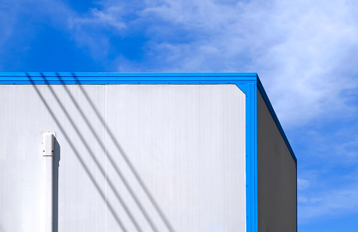 Air conditioning pipeline on white wall of office container against cloud on blue sky