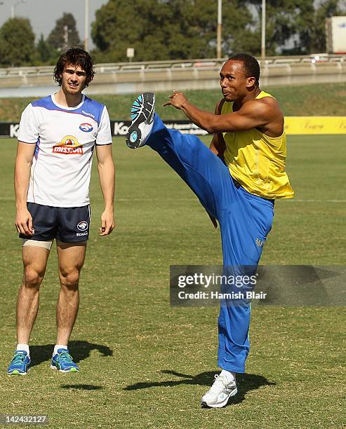 Jamaican 4 x 100m relay world record holder Michael Frater kicks a football with Western Bulldogs' AFL player Easton Wood looking on at Whitten Oval...