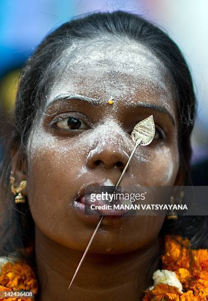 An Indian Tamil Hindu devotee with a steel rod pierced through her tongue takes part in a religious procession for Lord Murugan in New Delhi on April...
