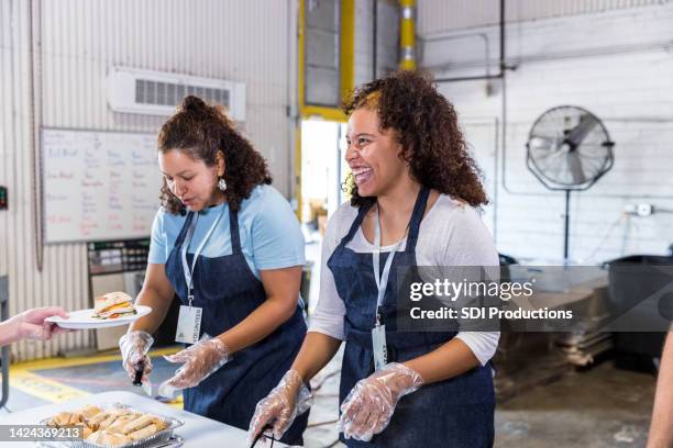 weibliche freiwillige servieren sandwiches - soup kitchen stock-fotos und bilder